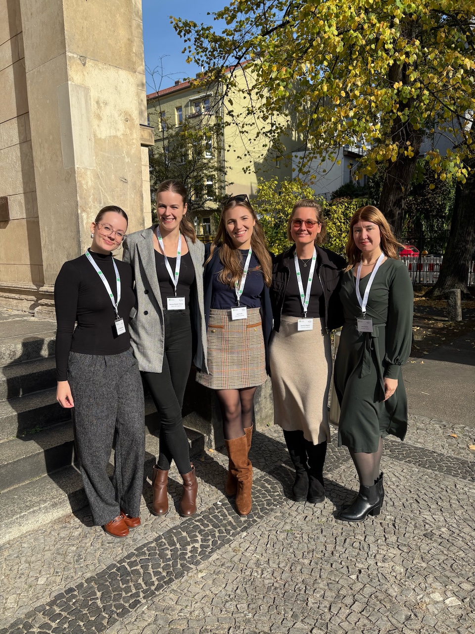 Eine Gruppe von fünf Frauen steht im Freien vor einer historischen Kulisse.